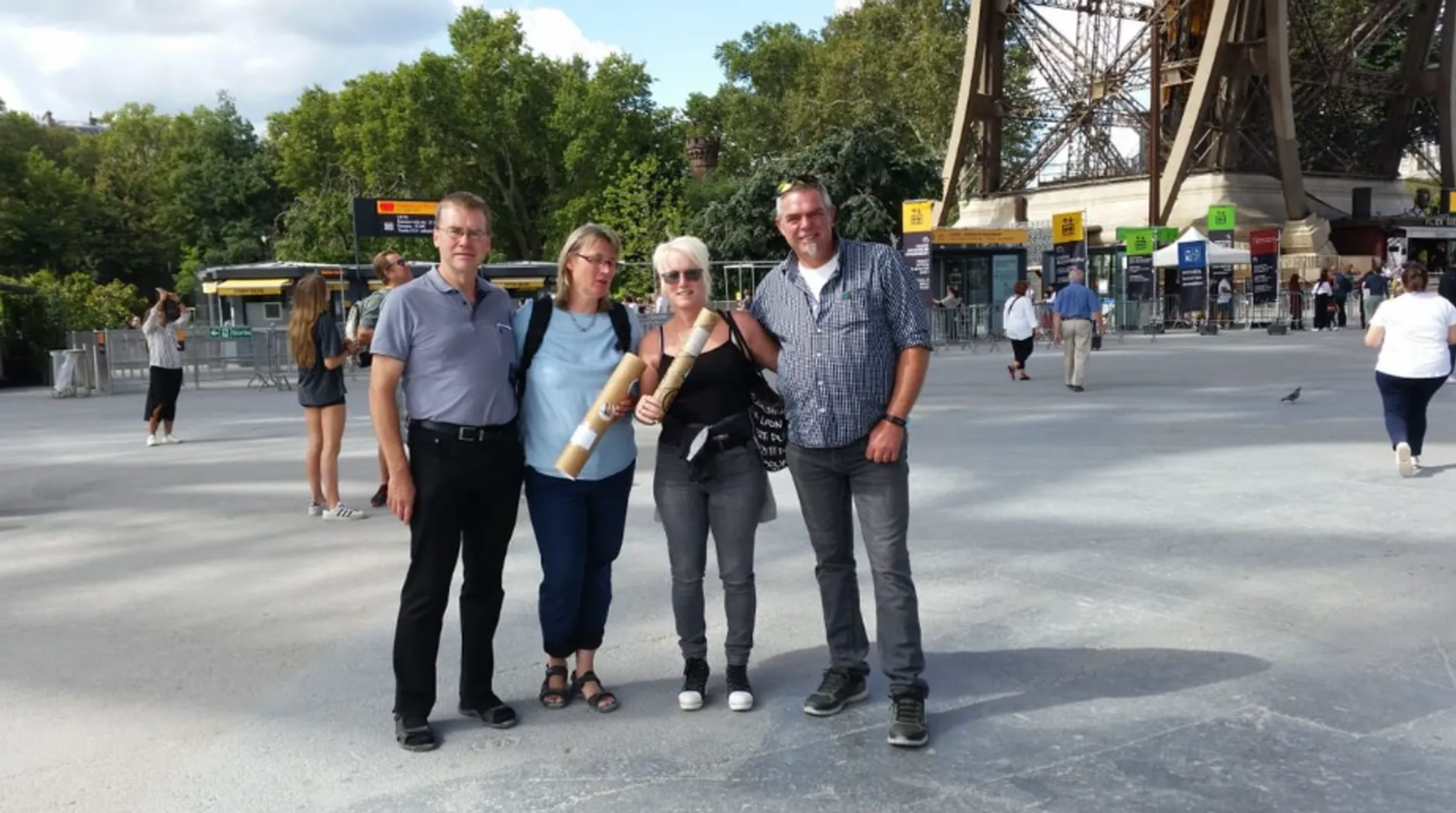 Vier Personen stehen vor dem Eiffelturm in Paris und posieren gemeinsam für ein Gruppenfoto.