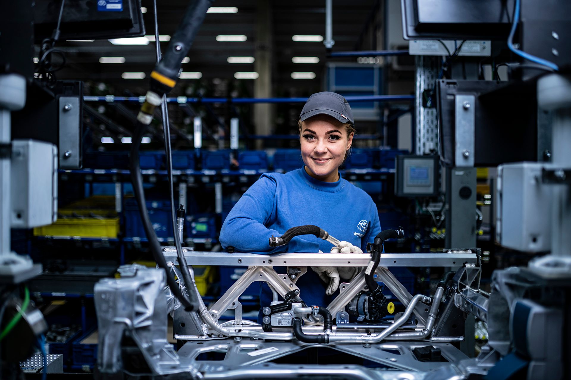 Person arbeitet an einem Metallrahmen in einer Fertigungsstation einer Automobilfabrik.