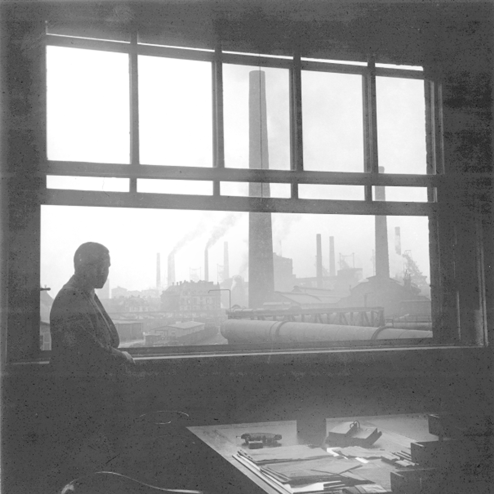 Silhouette eines Mannes am Fenster mit Blick auf die Bruckhausener Werksanlagen der August Thyssen-Hütte AG, um 1935.