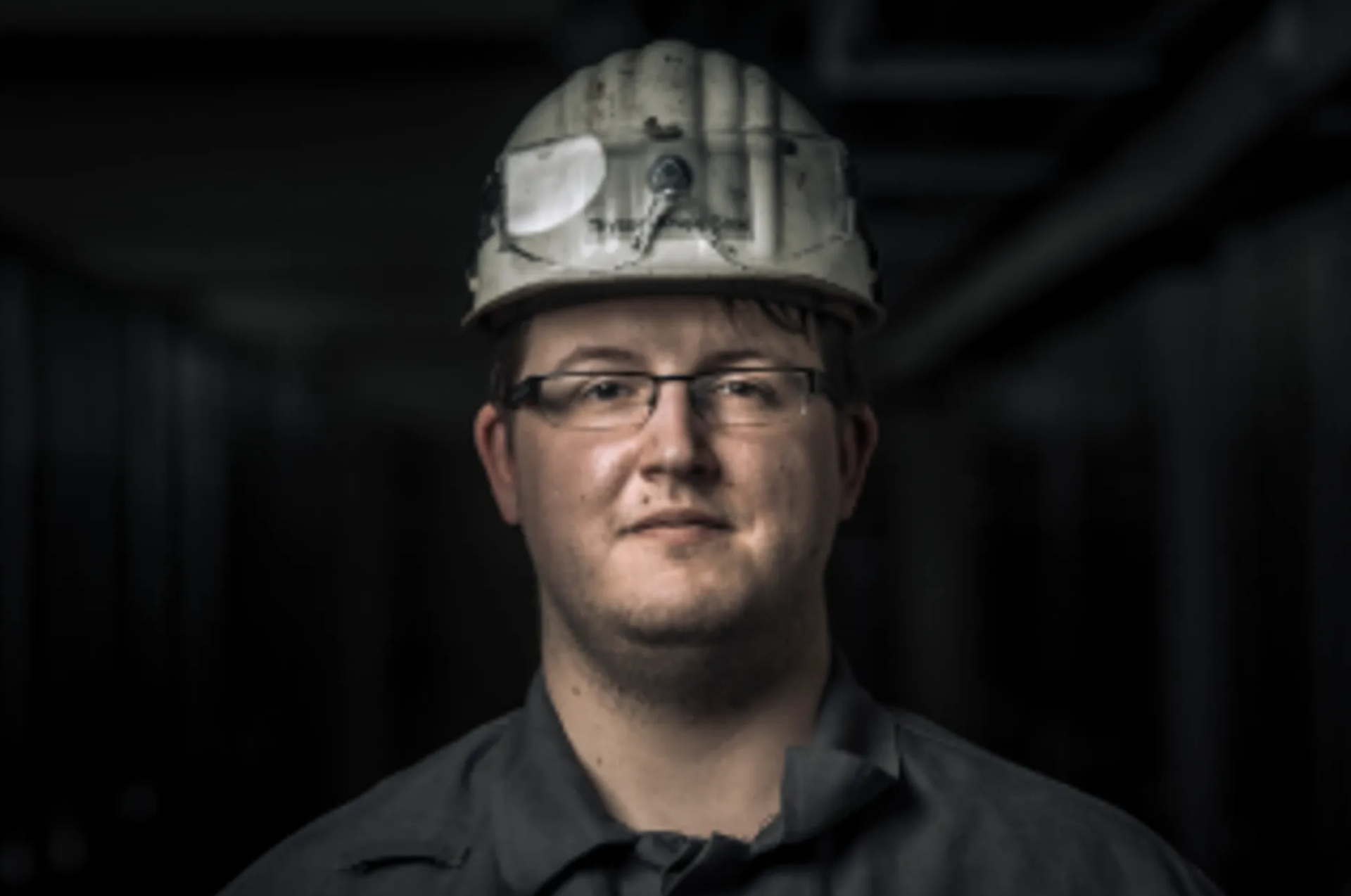Männlich gelesene Person mit schmaler Brille und Schutzhelm