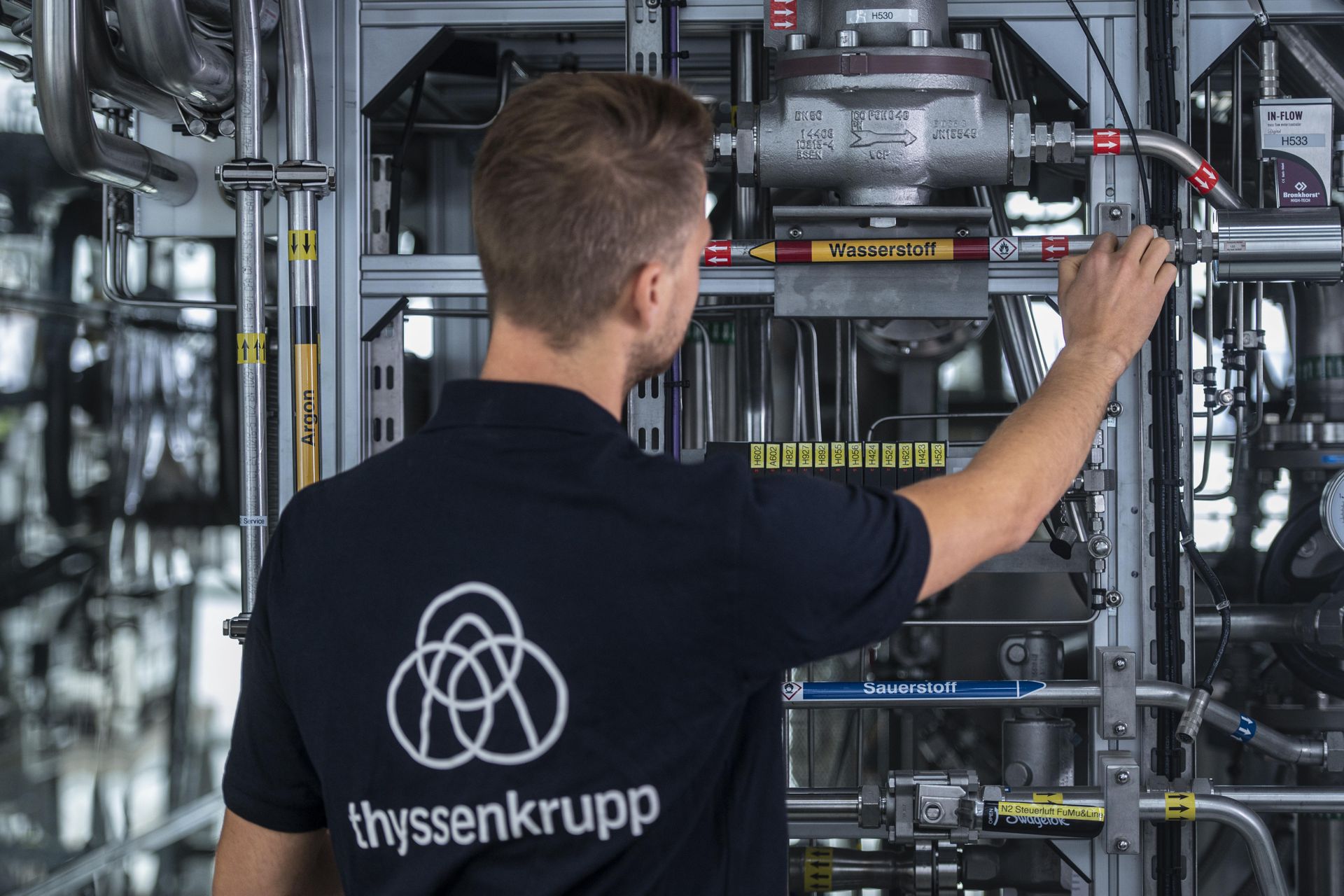 A thyssenkrupp employee operates the piping and valves of an industrial hydrogen pilot plant.