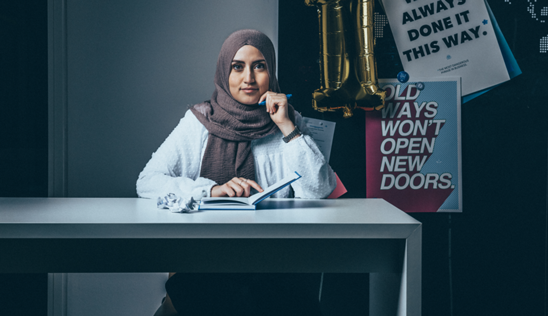 özlem Akdogan sits at a desk with an open notebook and a friendly expression on her face