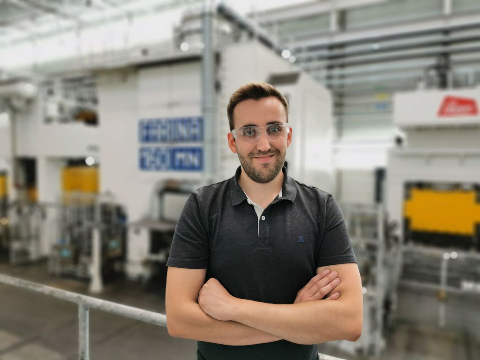 Portrait of Christopher Chaßeur, production expert at thyssenkrupp Homburg, in front of an automated forging line in a modern industrial environment.