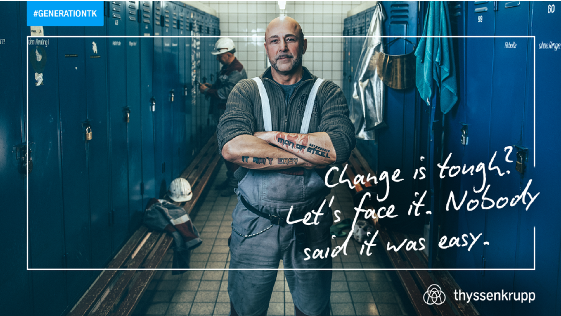 man standing in a locker room, arms crossed in front of his body, tough face, tattoo: Man of steel on his arms