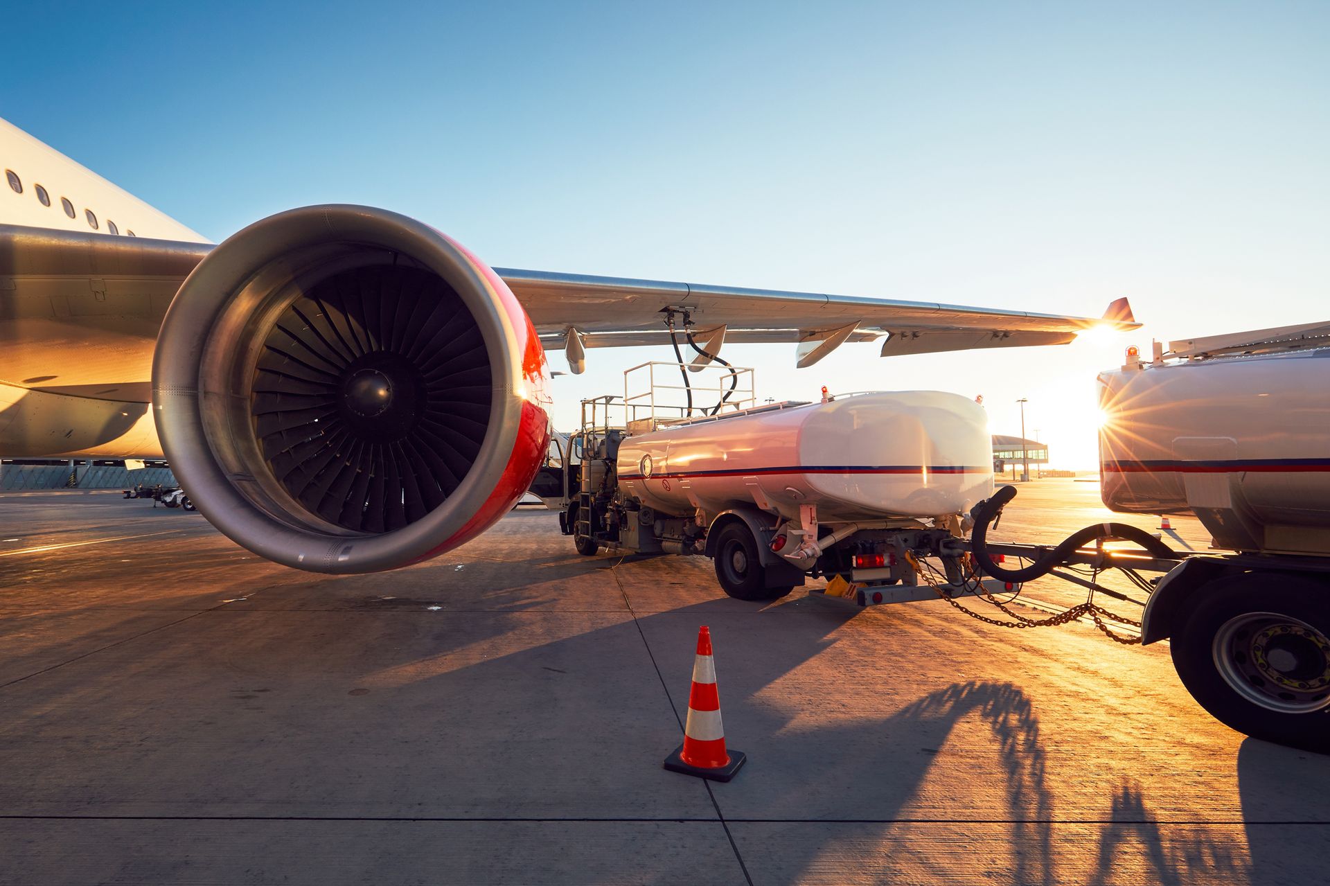 Tankfahrzeuge stehen während der Betankung unter der Tragfläche eines Flugzeugs.