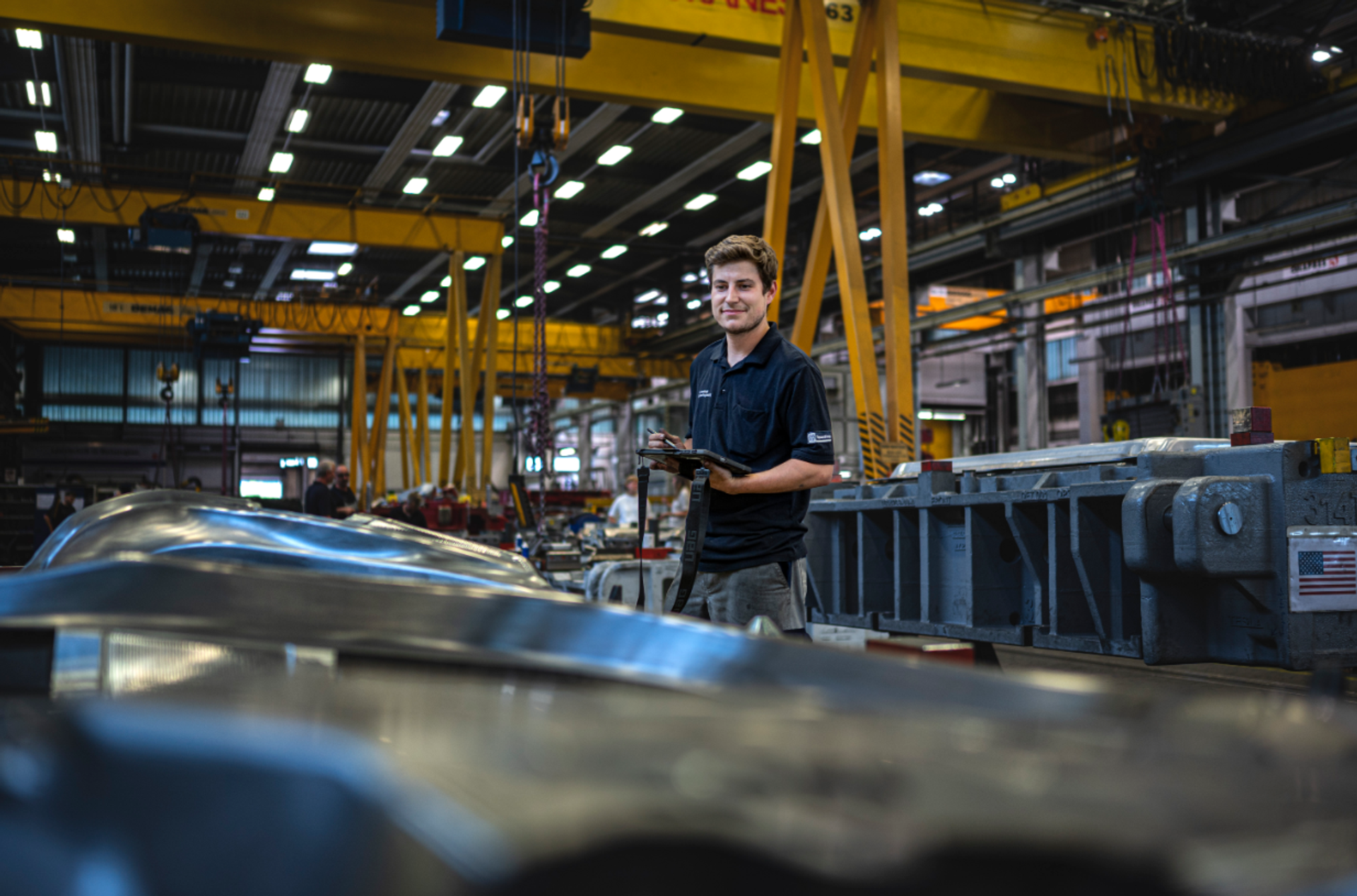 Mitarbeiter von thyssenkrupp in einer Produktionshalle bei der Fertigung und Qualitätskontrolle industrieller Komponenten.