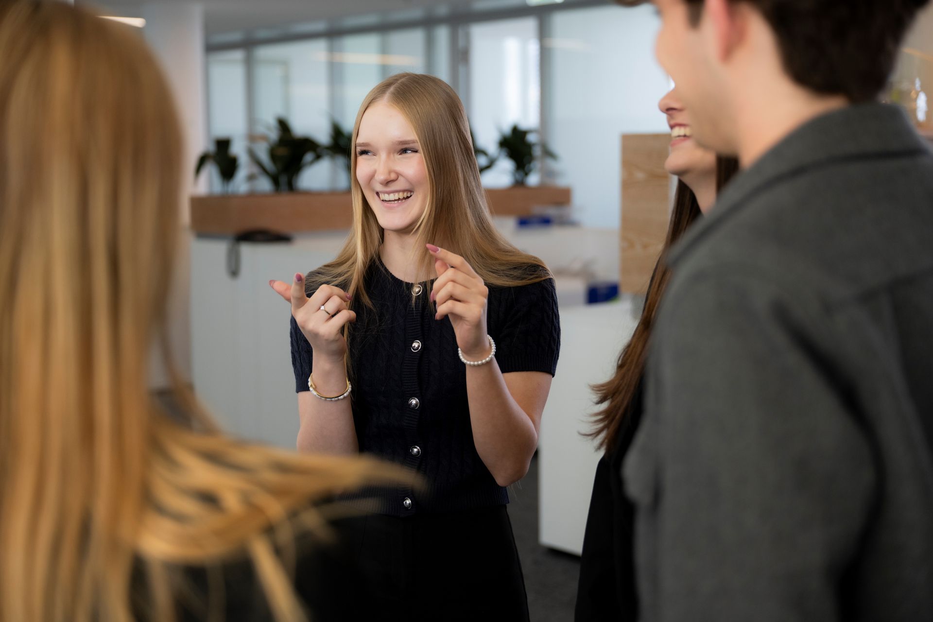Personen stehen zusammen in einem offenen Büro und unterhalten sich.