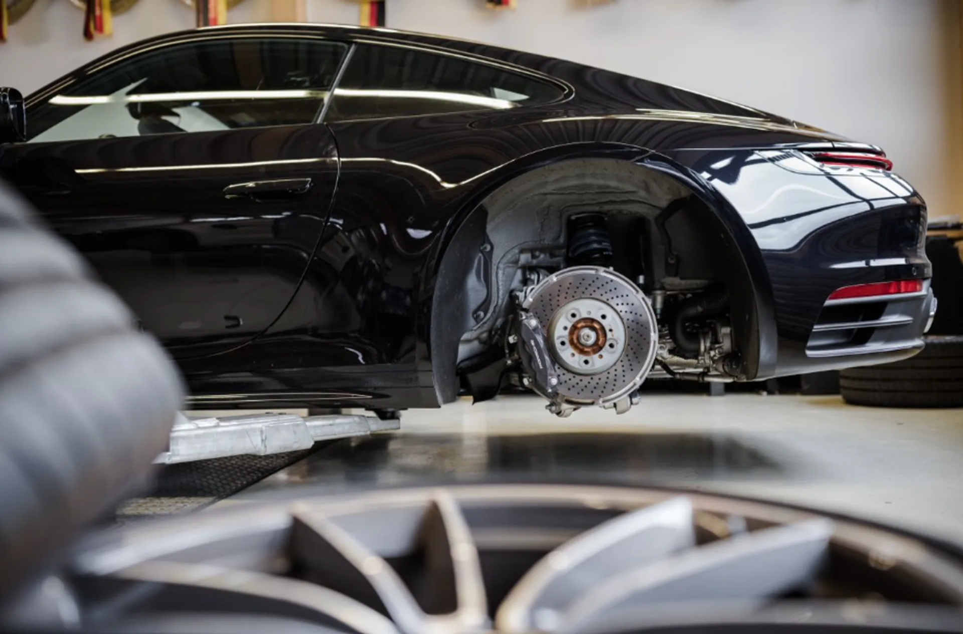 Sports car on lift with exposed rear wheel and suspension system showing semi active shock absorber setup in workshop environment