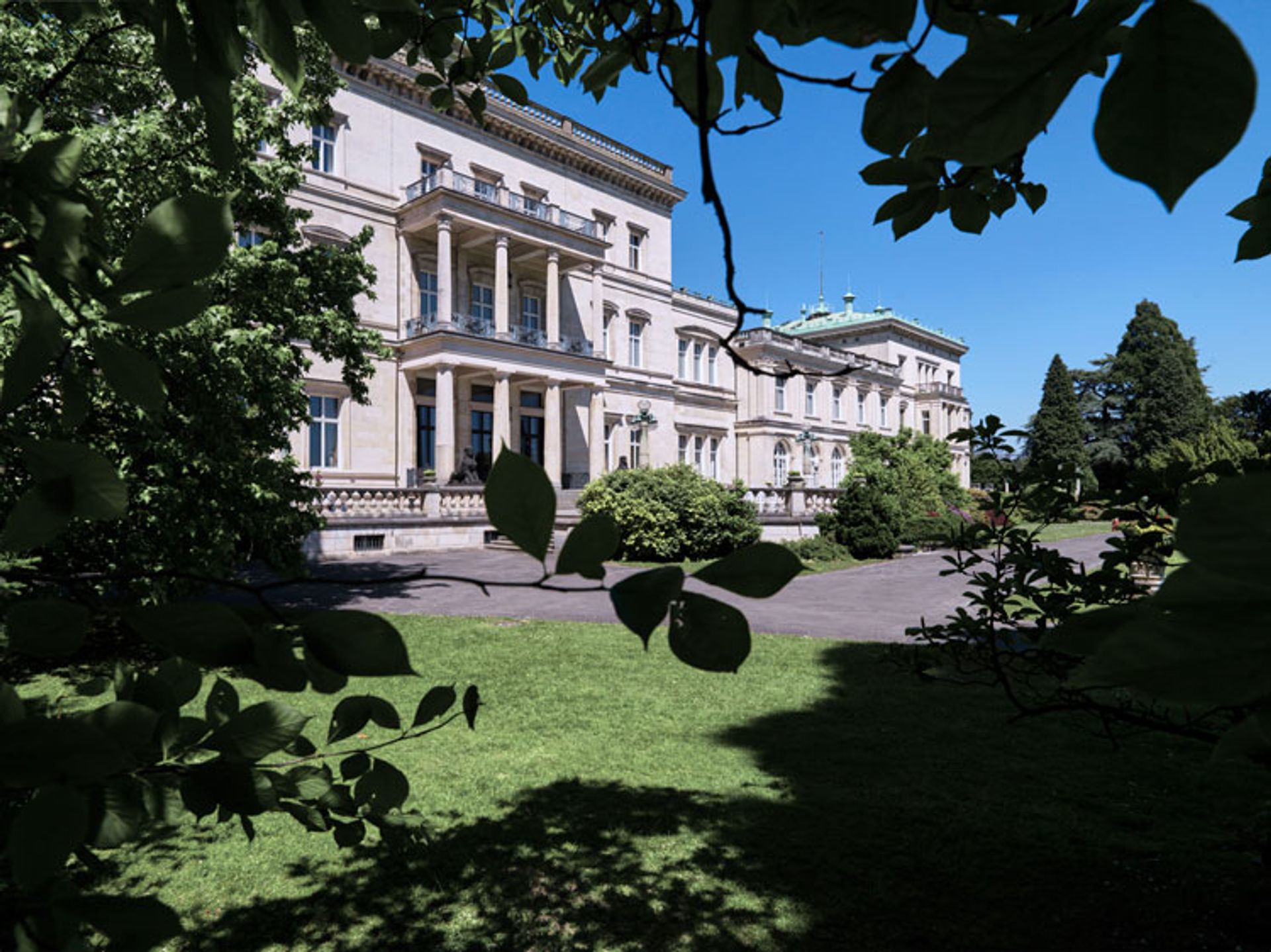 Blick durch Laub auf die Fassade der Villa Hügel