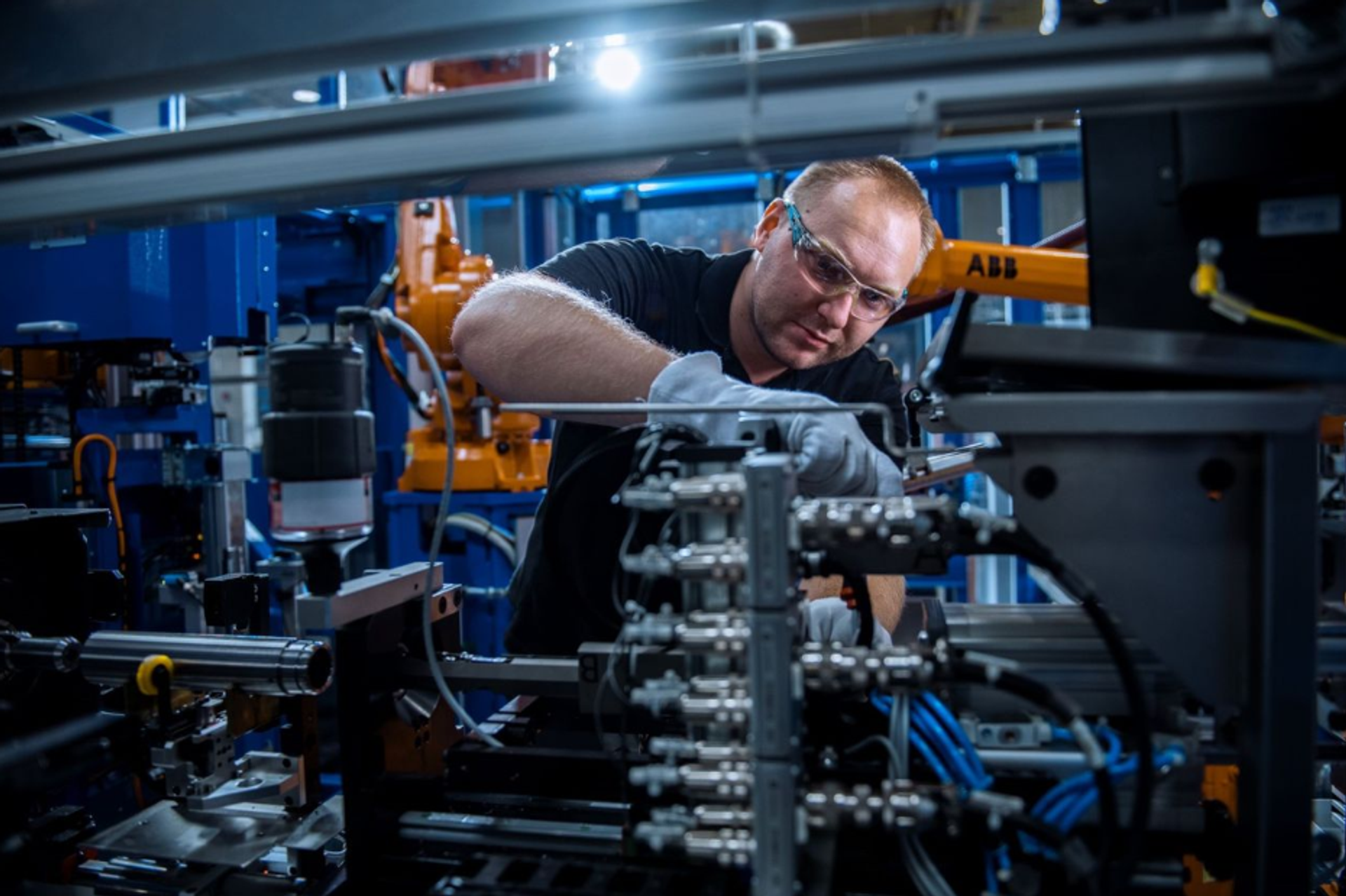 An employee of thyssenkrupp Dynamic Components assembling a multi-part rotor shaft in an automated manufacturing line.