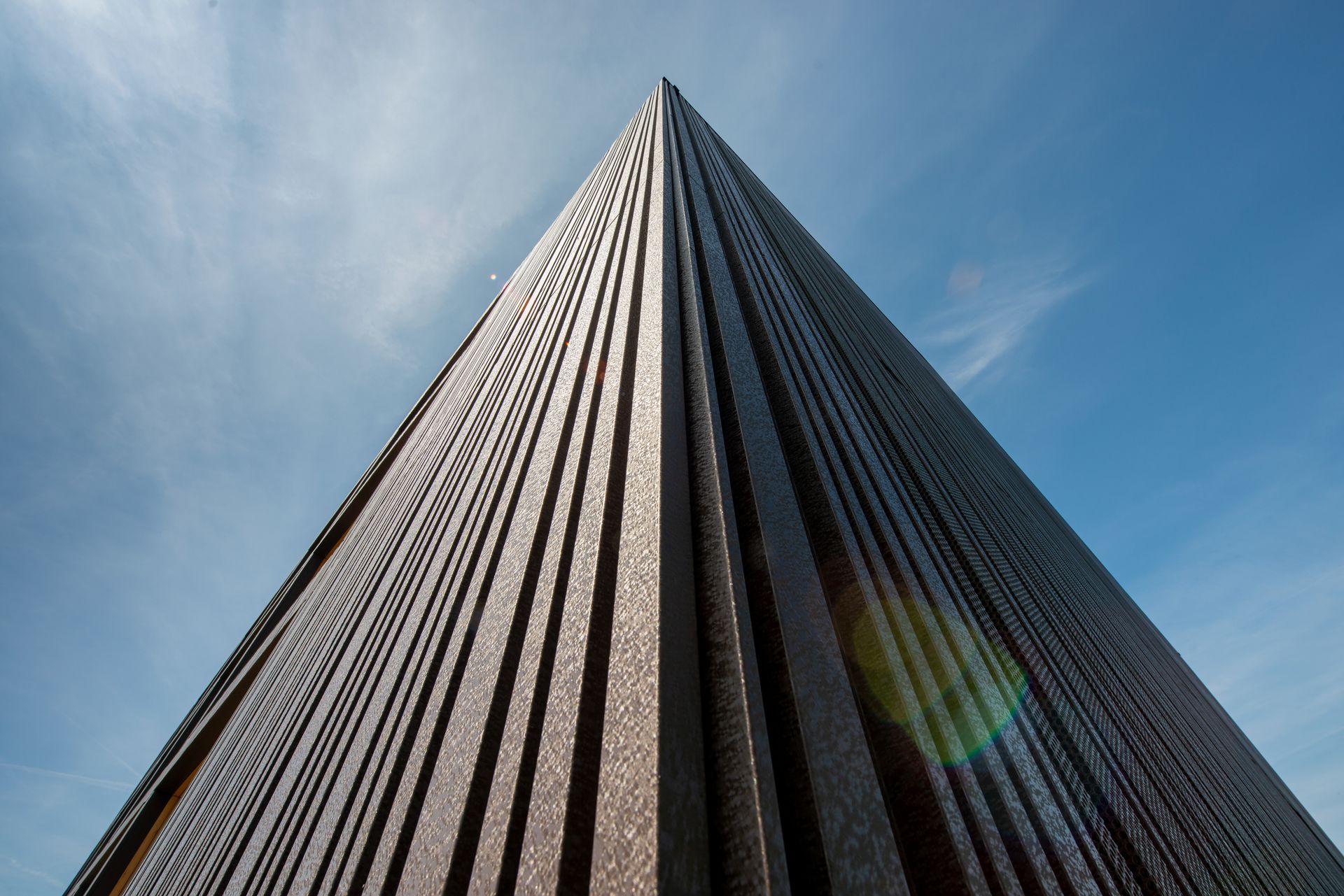 Nahaufnahme einer modernen Gebäudefassade mit pladur®-Profilen von thyssenkrupp Steel vor blauem Himmel.