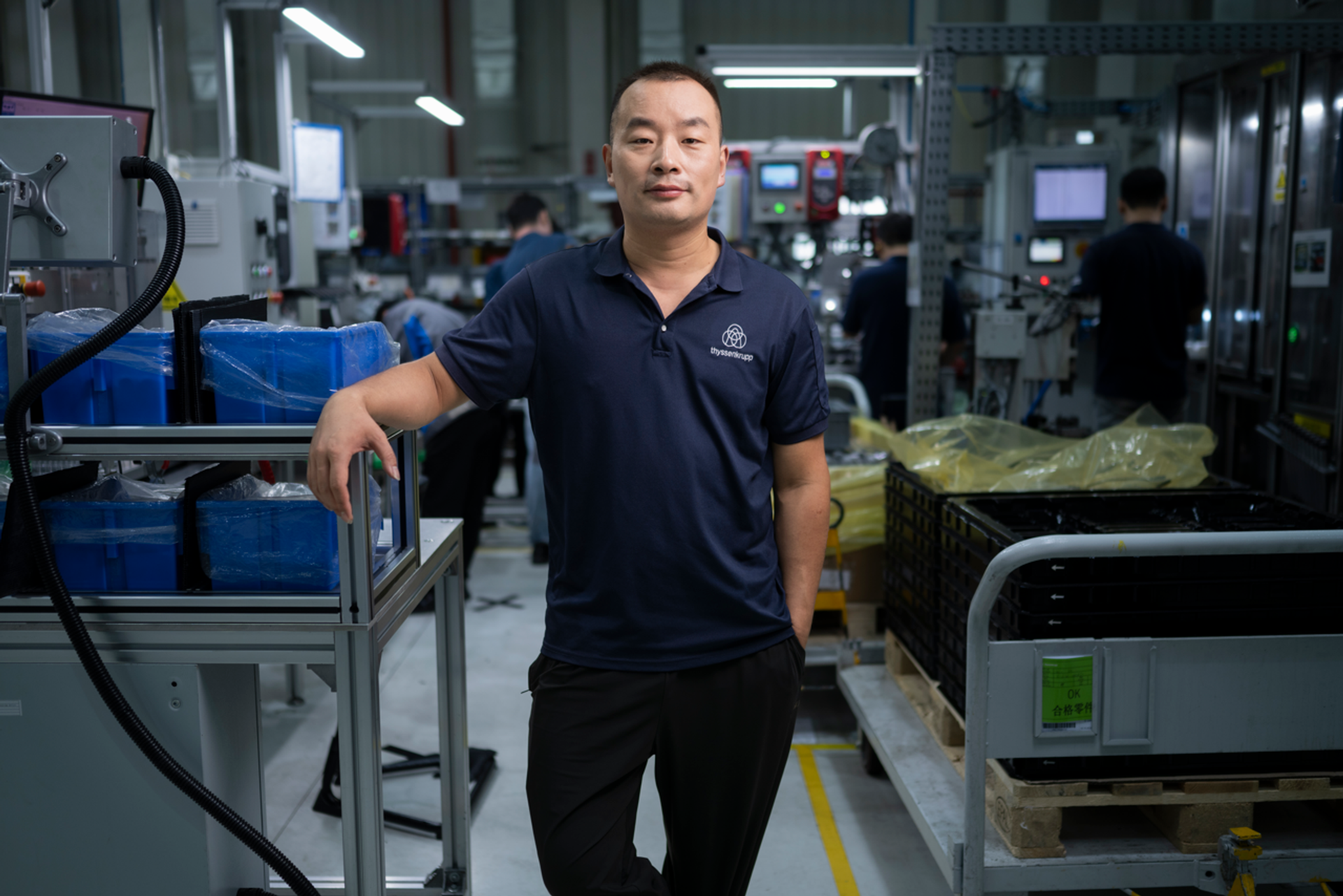 Eine Fachkraft aus der Chemie- und Verfahrenstechnik steht in einer Produktionsumgebung von thyssenkrupp, umgeben von industriellen Anlagen und technischen Komponenten. Das Bild symbolisiert Prozessengineering, Materialforschung, Anlagenbetrieb und moderne verfahrenstechnische Innovationen.