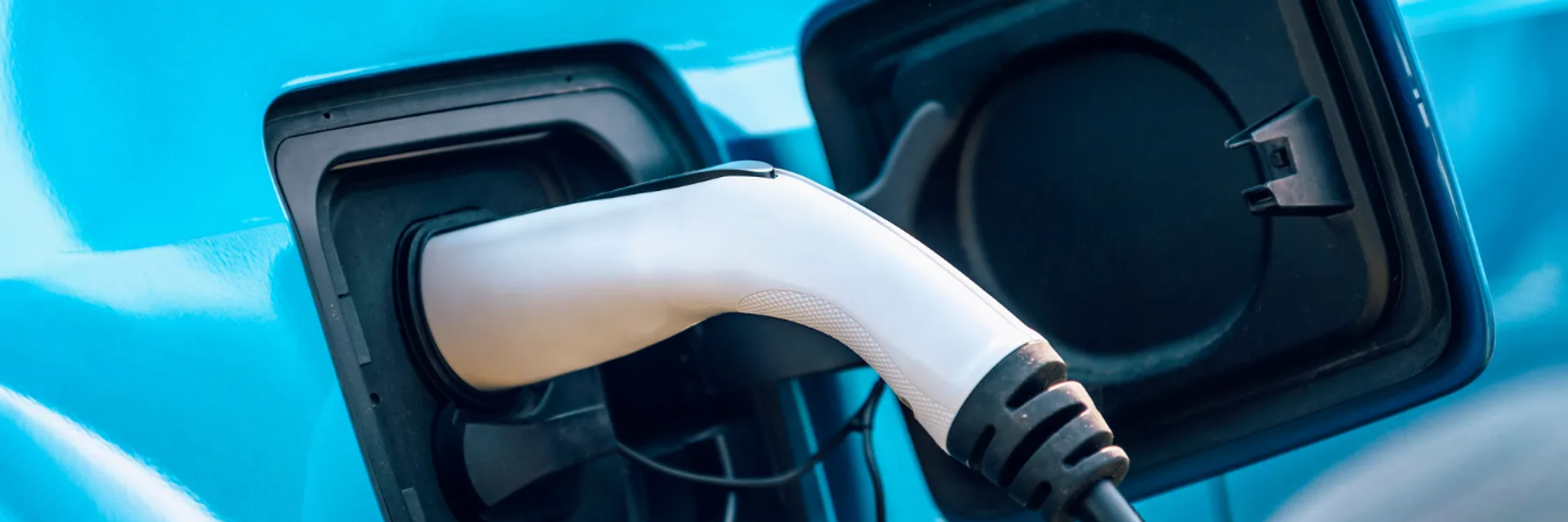 Nahaufnahme eines Ladesteckers, der an ein Elektroauto angeschlossen ist – Laden eines E-Fahrzeugs im Alltag.