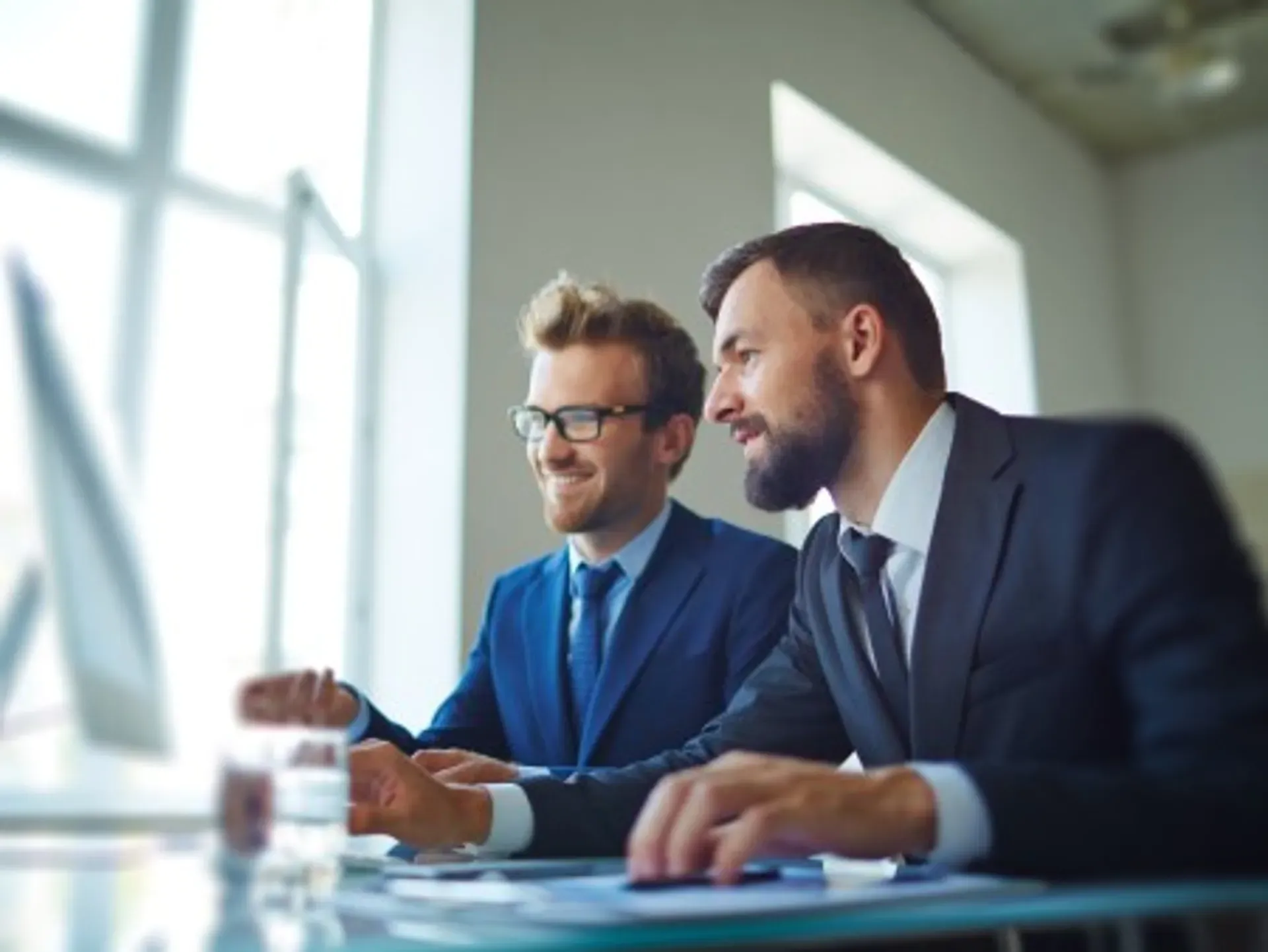 Zwei Männer im Anzug besprechen eine Aufgabe im Büro