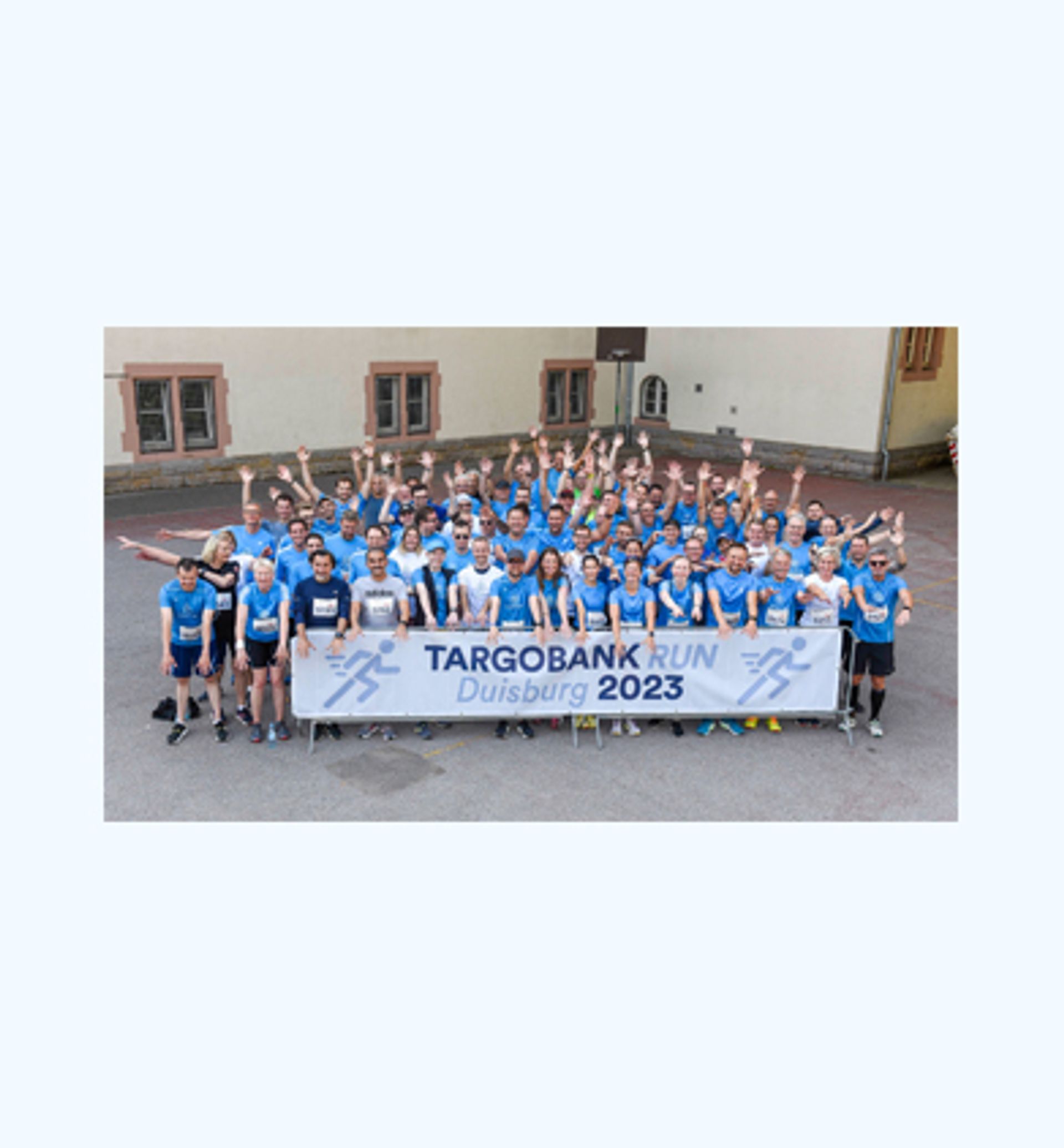 Group photo: thyssenkrupp employees in blue running shirts cheering behind a Targobank Run Duisburg banner.