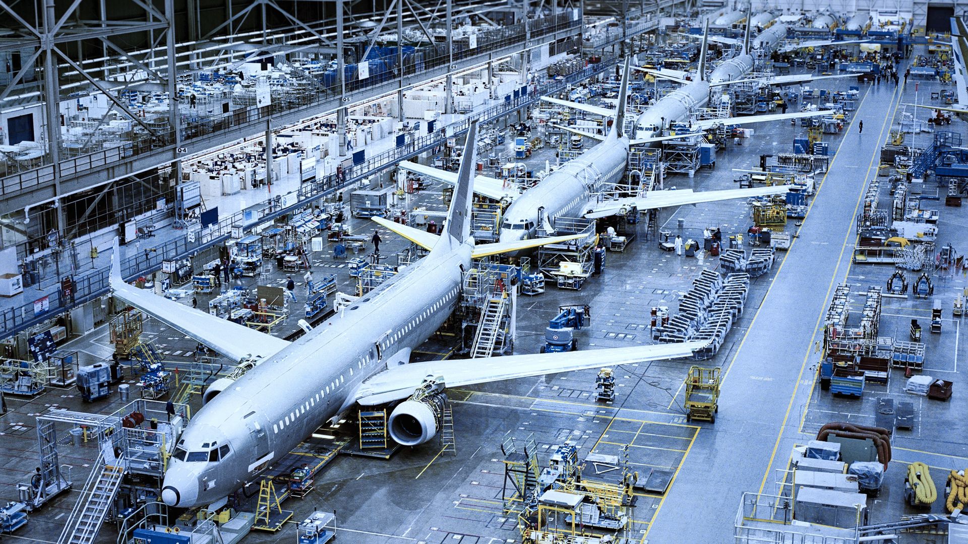 Mehrere Passagierflugzeuge während der Montage in einer großen Produktionshalle.