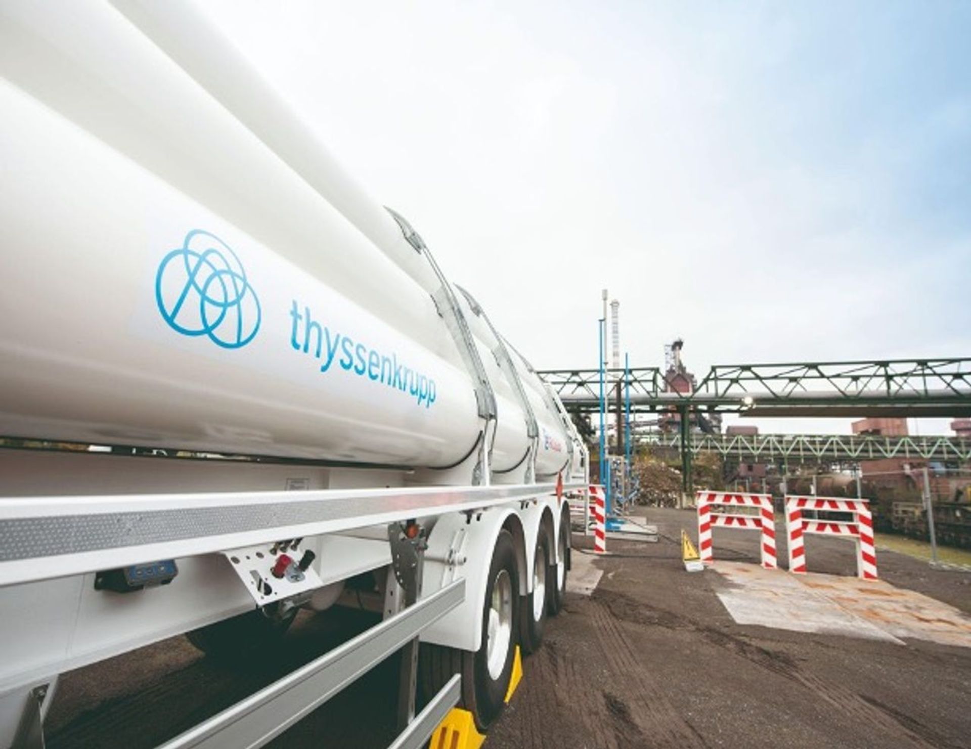 A tanker truck with the thyssenkrupp logo in front of an industrial facility.