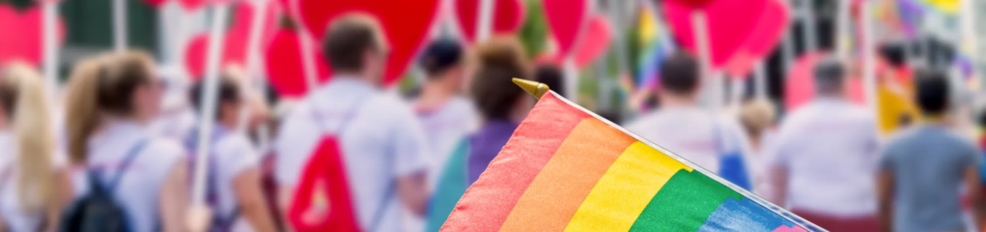 Flagge in Regenbogen-Farben, verschwommener Hintergrund einer Demonstration