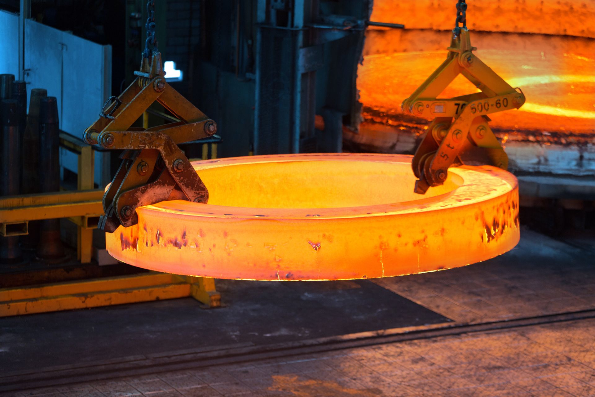 Glühender Stahlring wird in einem thyssenkrupp-Werk mit Greifvorrichtungen aus dem Ofen gehoben.