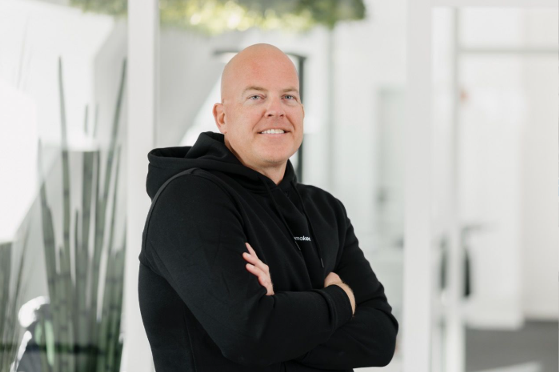 Portrait of Christian Jabs, Managing Director of pacemaker.ai, in the office with his arms folded.