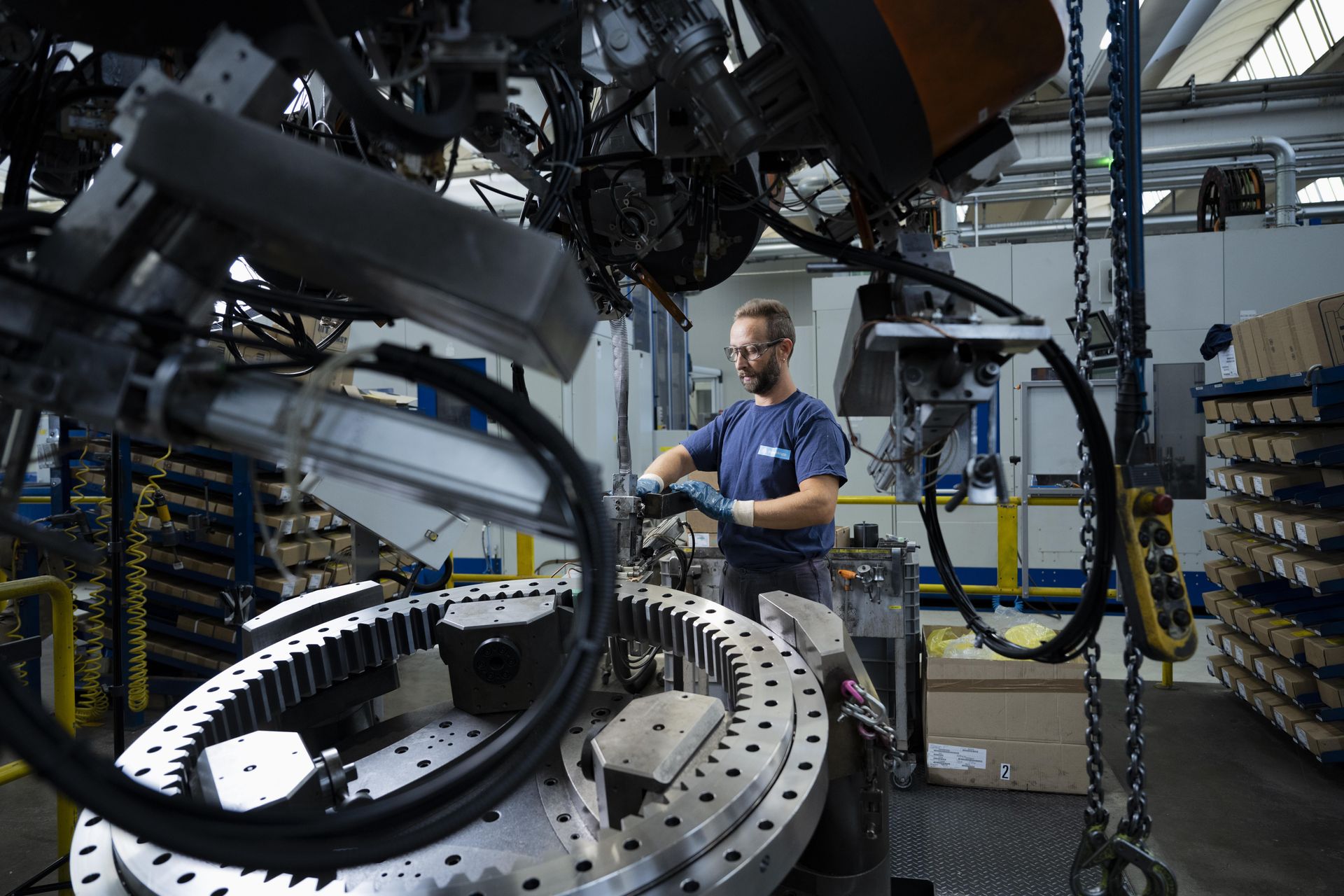 An employee is working on a large roller bearing for wind turbines in a production hall.