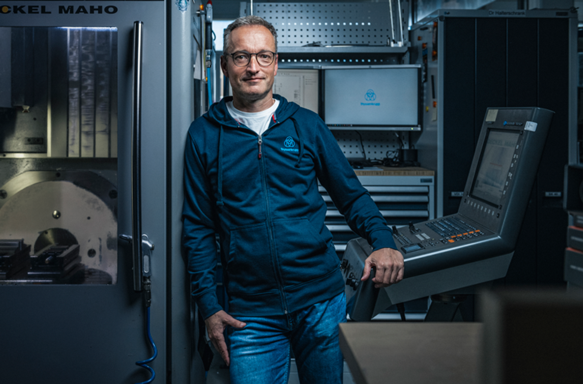männlich gelesene Person mit thyssenkrupp Sweatjacke, graue kurze Haare, freundliches lächeln, runde Brille mit Kampagne #GENERATIONTK