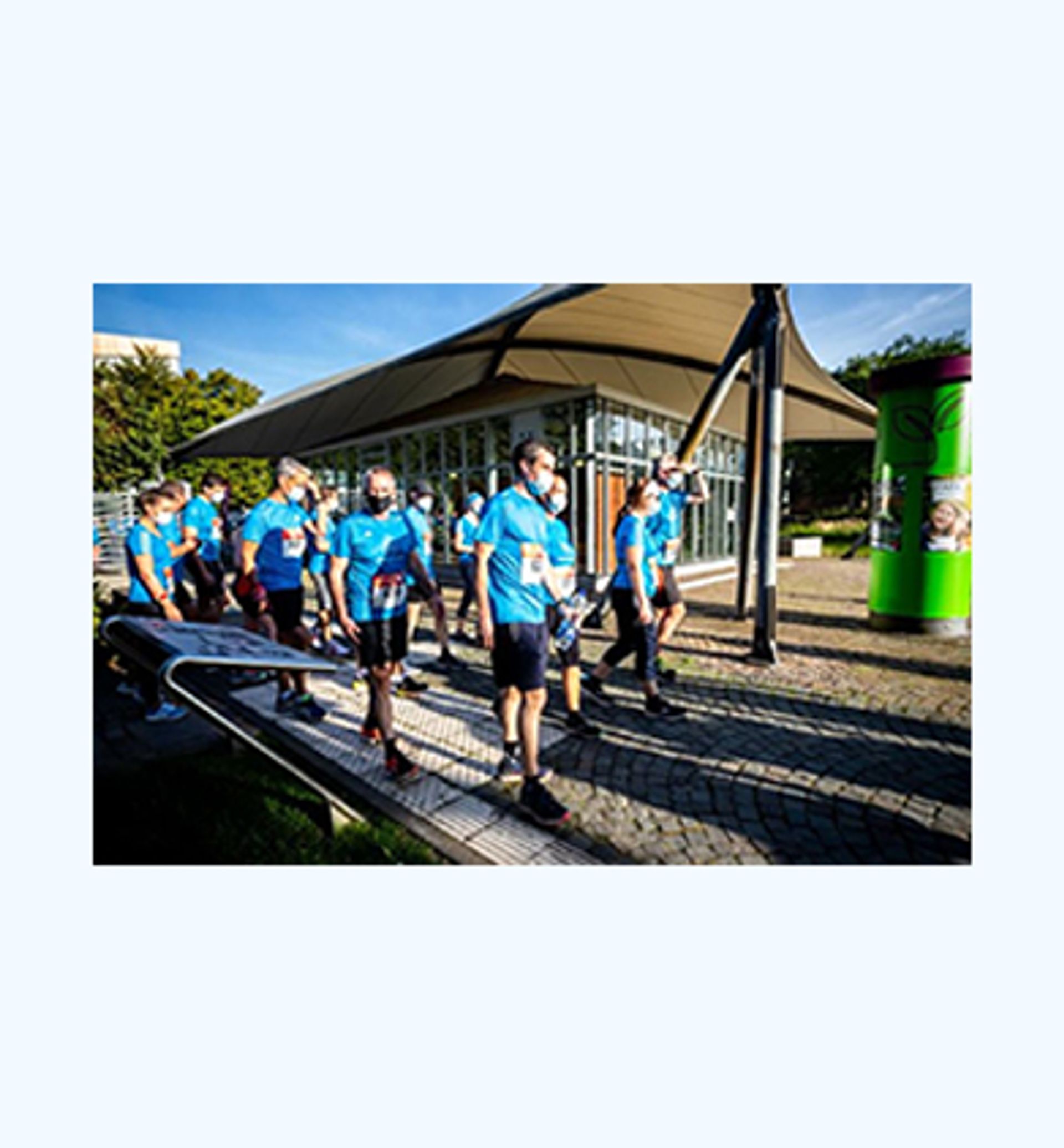 Foto thyssenkrupp Mitarbeitende in blauen Laufshirts beim Startpunkt eines Firmenlaufs