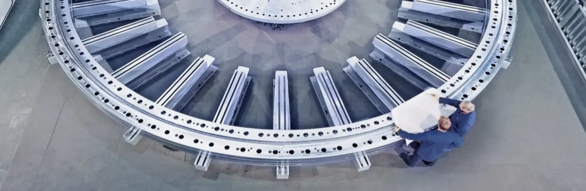 Large slewing bearing ring in a production facility with technician, used in wind turbines for efficient renewable energy generation.
