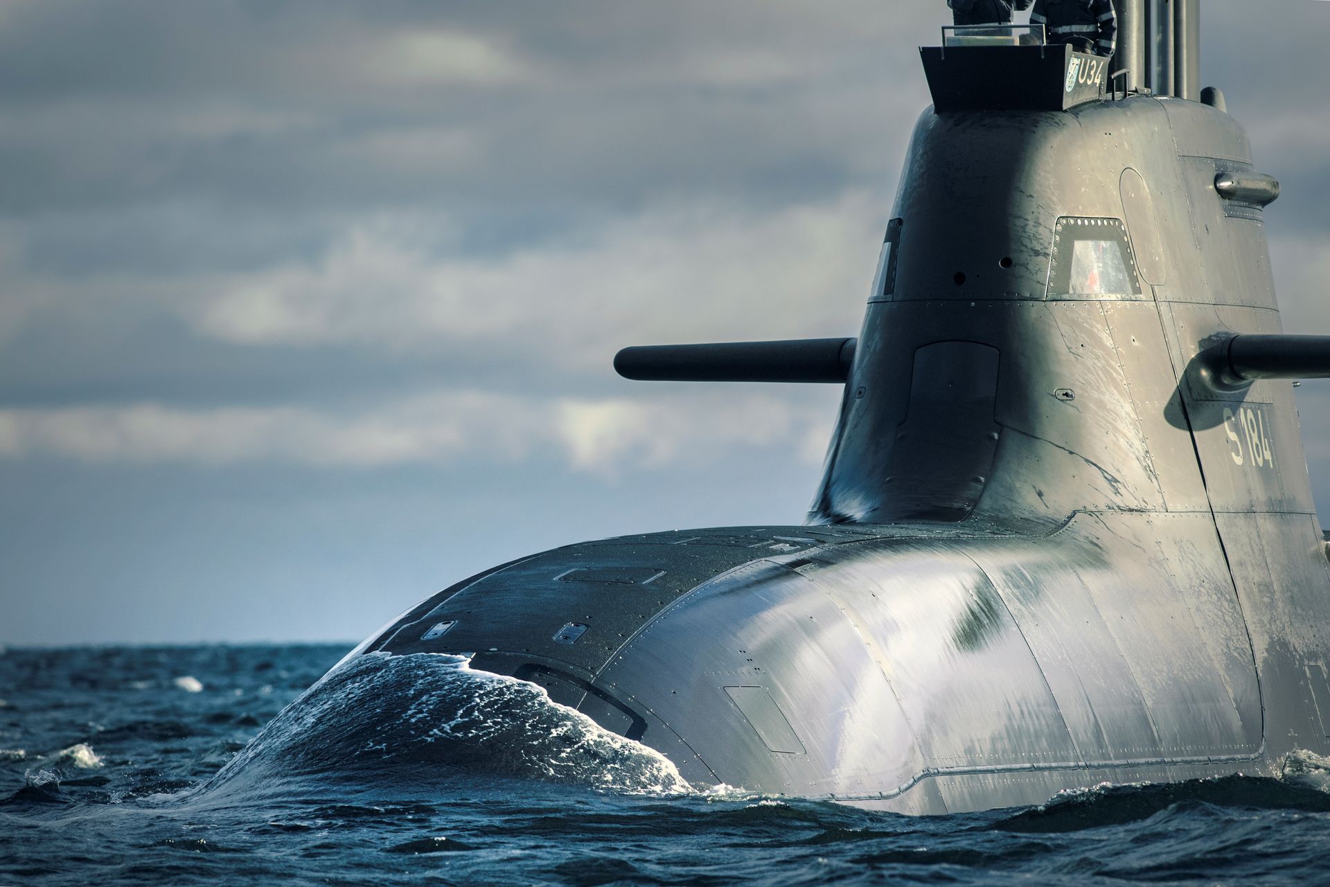 Modernes U-Boot taucht auf hoher See unter bewölktem Himmel auf.