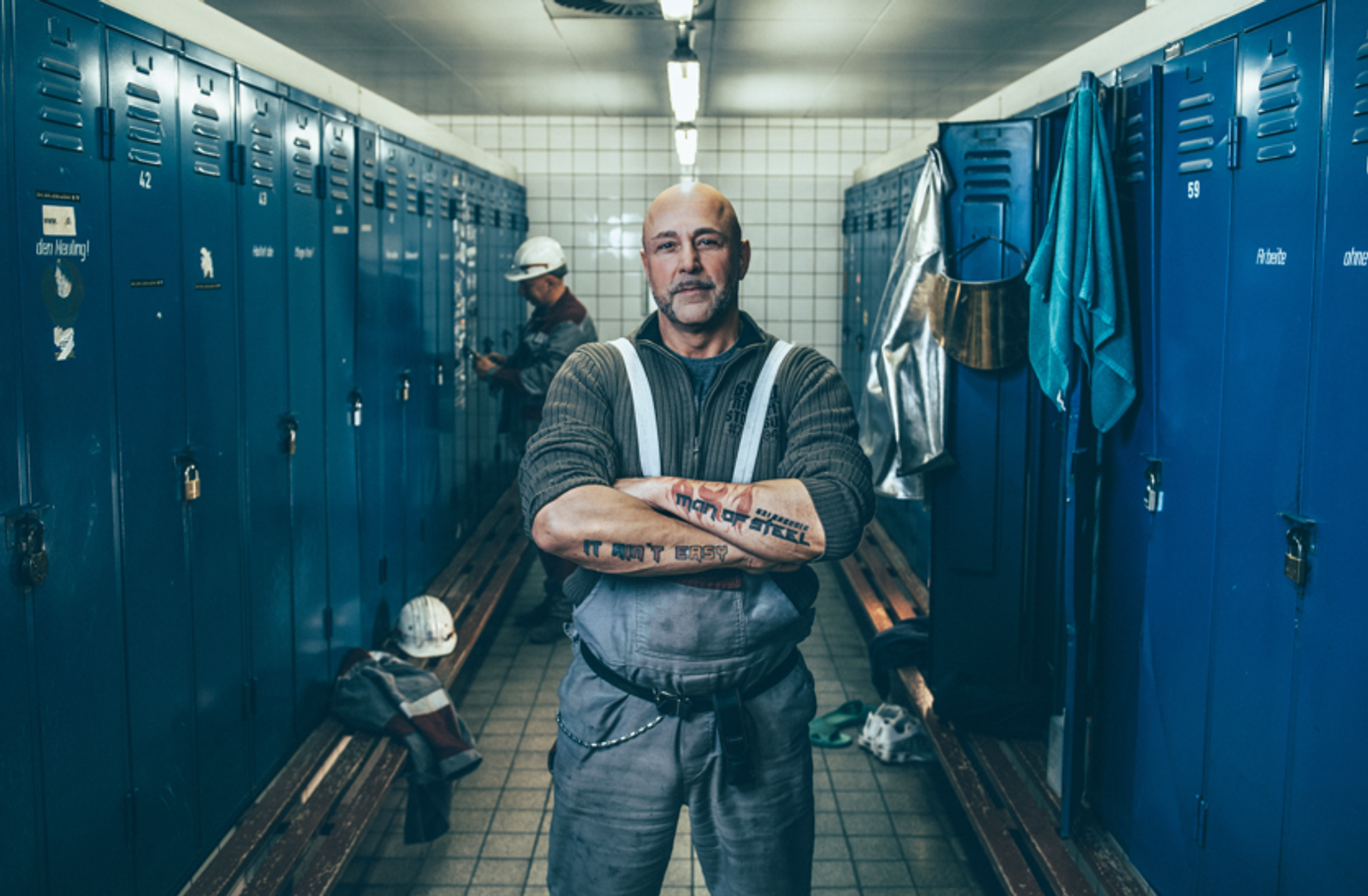 männlich gelesene Person mit verschränkten armen und starkem Blick
