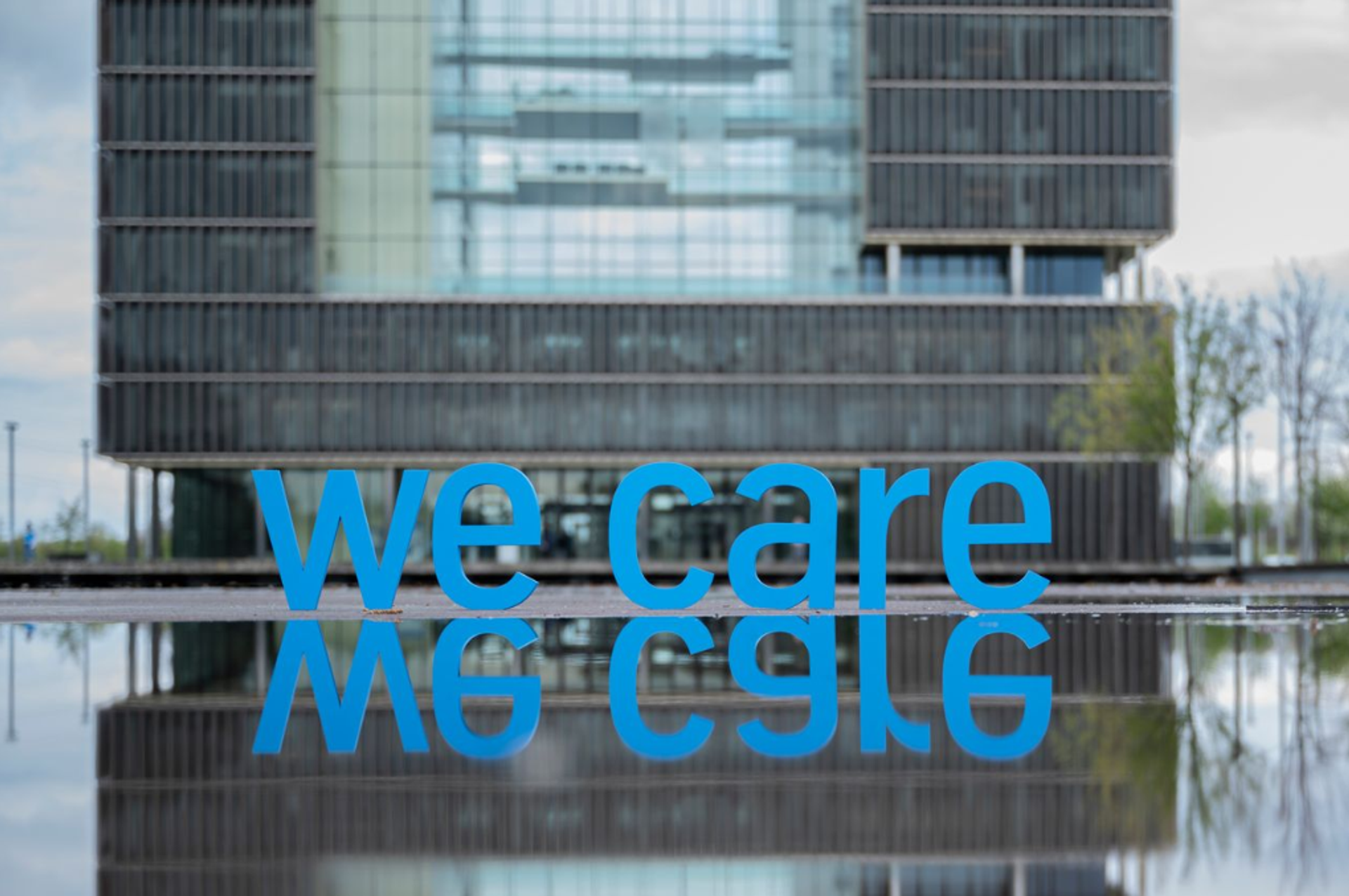 Visualisierung: blauer „we care"-Schriftzug in der Wasserachse vor dem thyssenkrupp Quartier, Symbol des OSH-Programms.