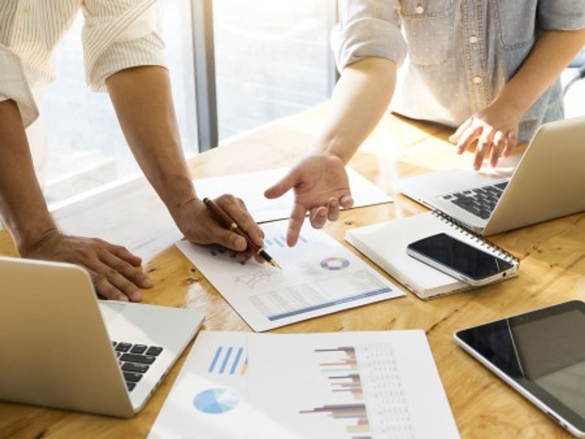 Team analysiert Finanzdaten und Diagramme am Laptop im modernen Büro und plant gemeinsam Geschäftsstrategie anhand von Statistiken und Berichten.