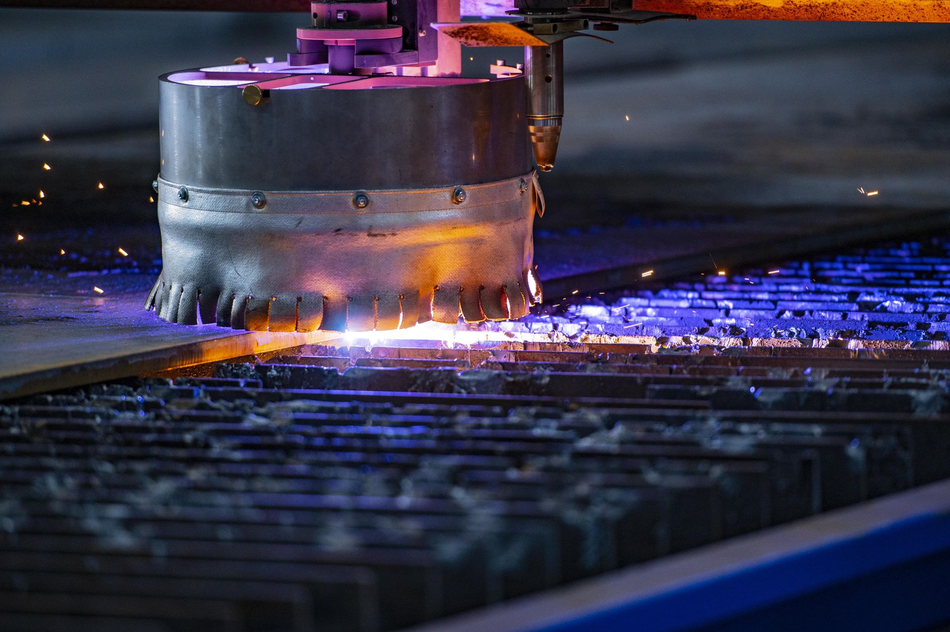 Stahlblech wird in einer industriellen Schneidanlage zugeschnitten, wobei Funken entstehen.
