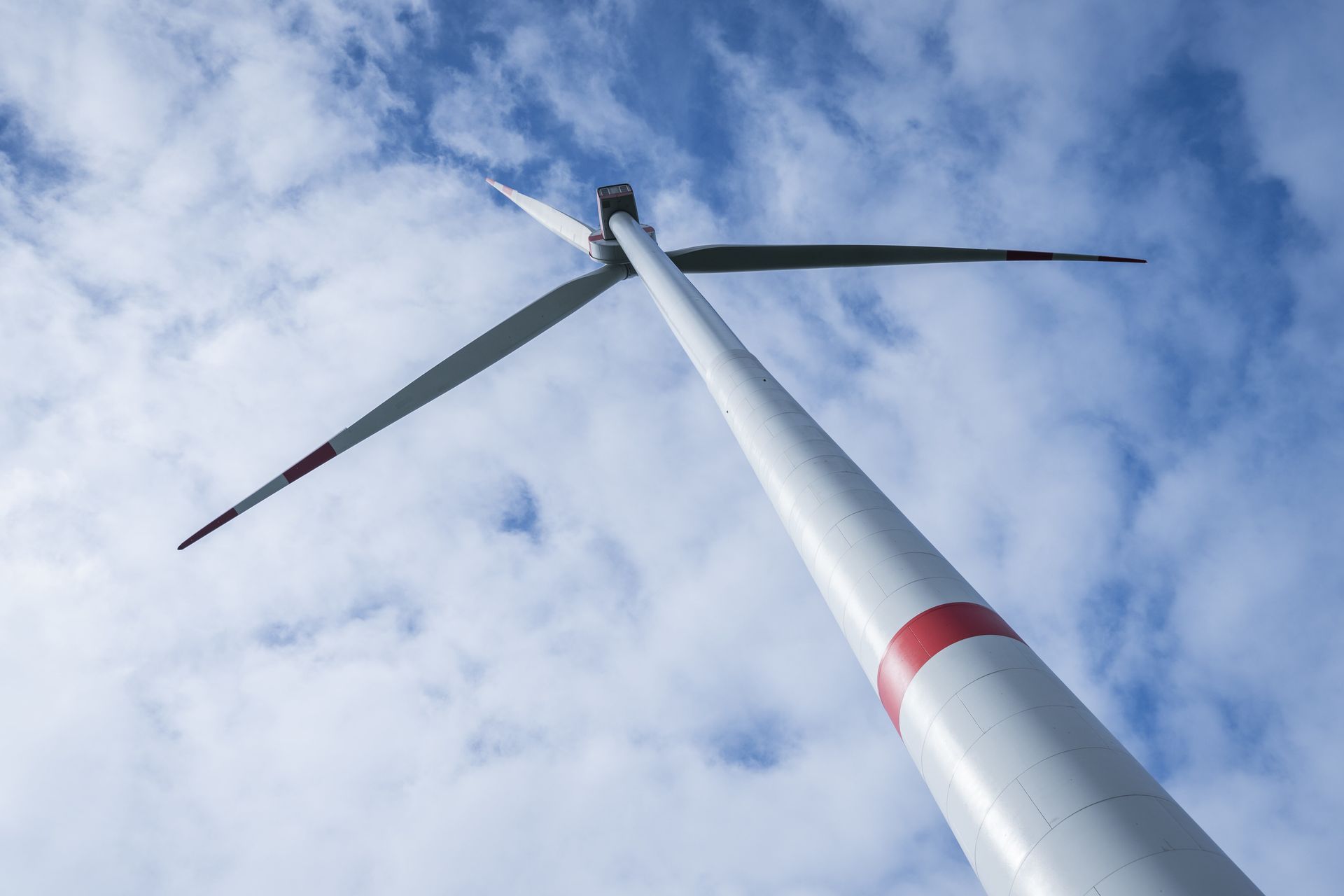 Windkraftanlage aus der Froschperspektive vor blauem Himmel.