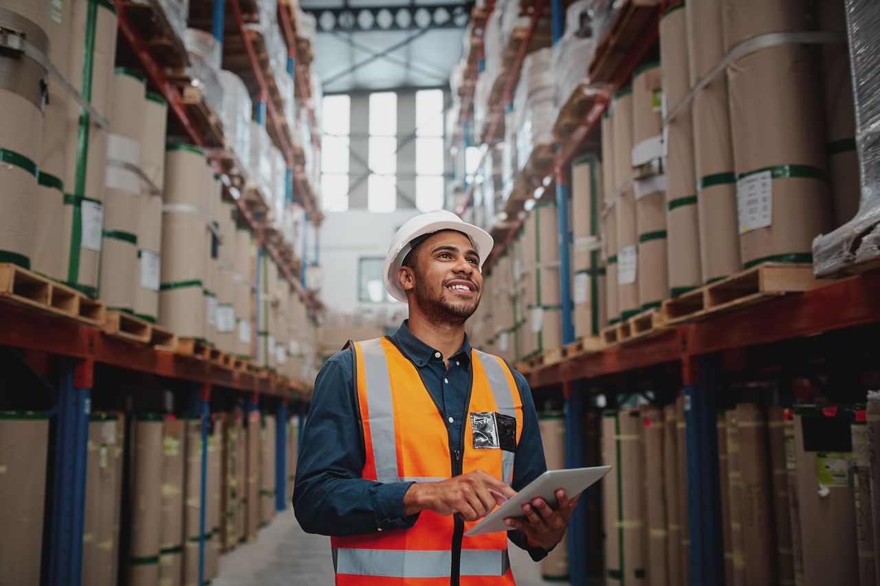 male employee consulting tablet in warehouse while conducting inventory management as a 3PL