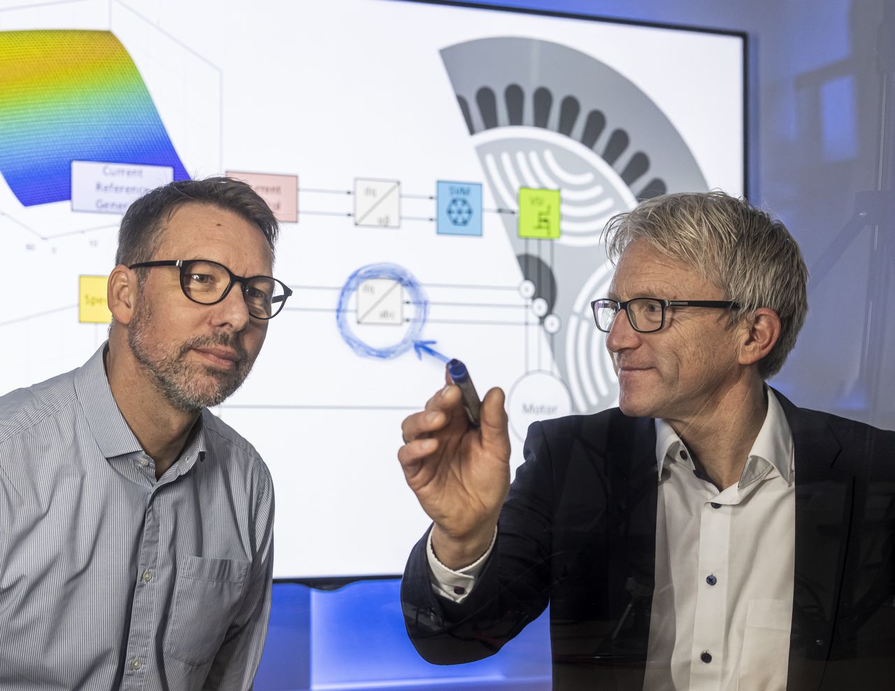 Ingenieur im TechCenter analysiert Schaubild eines komplexen Systems mit seinem Kollegen