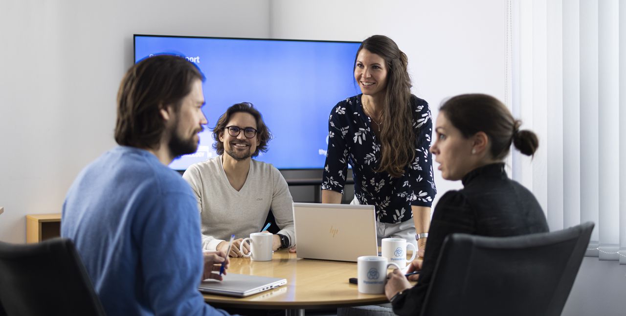 Je zwei Frauen und Männer halten gut gelaunt eine Team-Besprechung im TechCenter 
